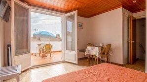 Ein Schlafzimmer mit einem Bett, einem Balkon mit Tisch und Stühlen sowie einem Deckenventilator.