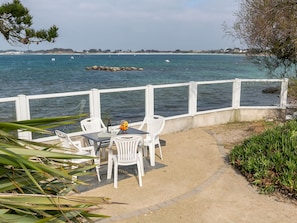 Guests can enjoy a tranquil seating area overlooking the water, featuring a table, chairs, and a beautiful view.