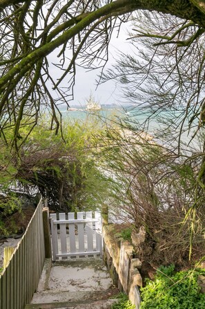 Stroll down to the beach from this charming staircase, surrounded by lush greenery and a serene body of water in the distance.