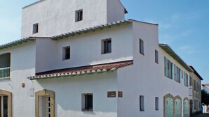 Un bâtiment blanc doté de nombreuses fenêtres et portes, d’un balcon et d’une enseigne indiquant « Rue du Vibre ».
