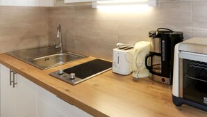 Une cuisine moderne équipée d’un évier en acier inoxydable, d’une plaque de cuisson électrique intégrée, d’une machine à café et d’un grille-pain.