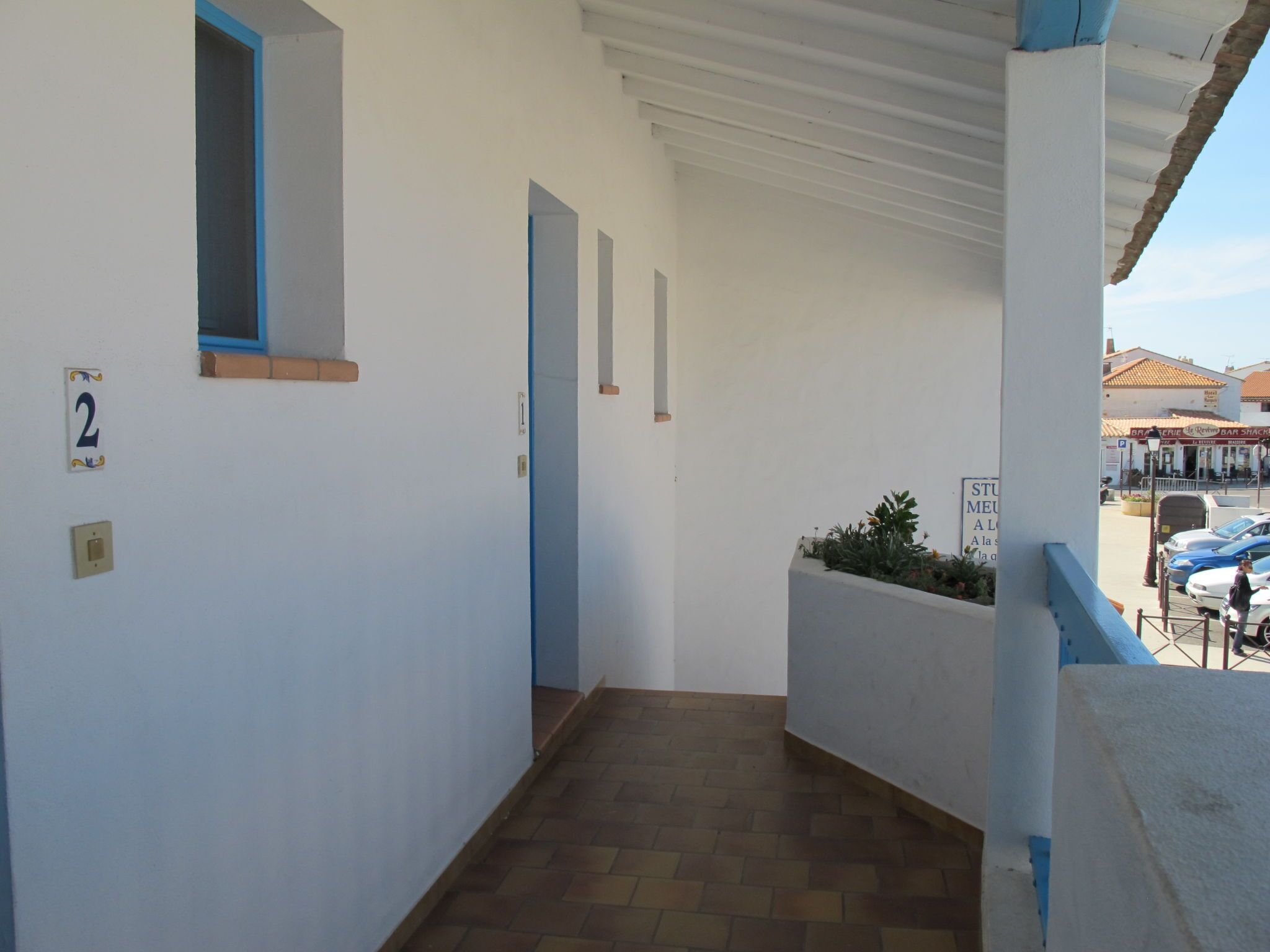 A corridor with a tiled floor, a number '2' sign, and a window with blue trim.