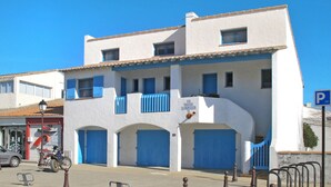 Ein weißes Gebäude mit blauen Fensterläden und einem Schild, auf dem 'LE SOLEIL CAMARGUAT' steht.