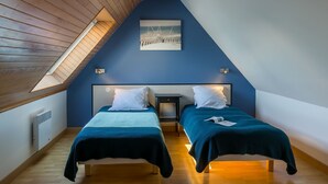 A room with two beds, a sloped ceiling, and a skylight. - Le Triskell by Interhome (Cléder)
