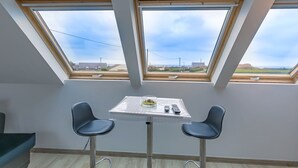 A room with a skylight, two chairs, a small table, and a view of the landscape.