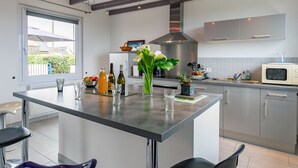A modern kitchen with a central island, stainless steel appliances, and a large window.