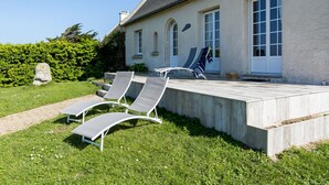 A house with a patio area featuring two lounge chairs and a small table.
