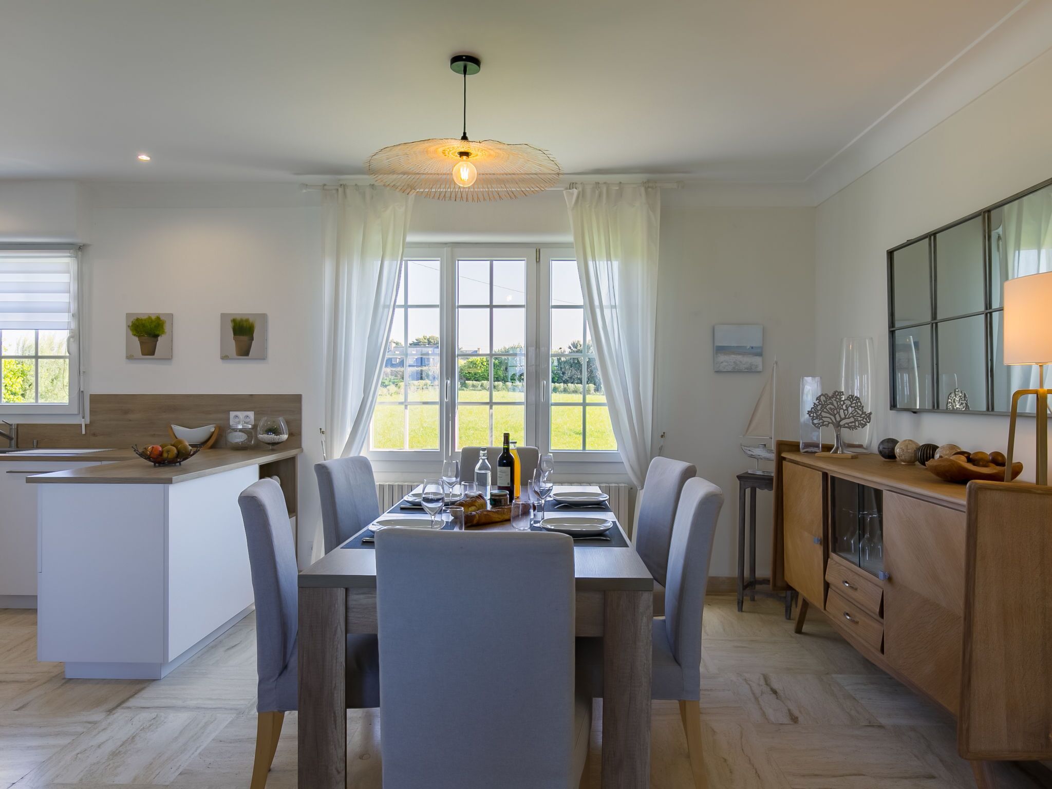 Une cuisine moderne avec un coin repas, de grandes fenêtres et une vue sur l’extérieur.