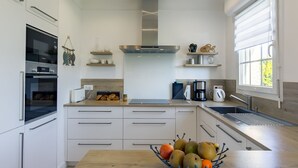A modern kitchen with white cabinetry, a Bosch oven, a coffee maker, and a fruit bowl on the counter.