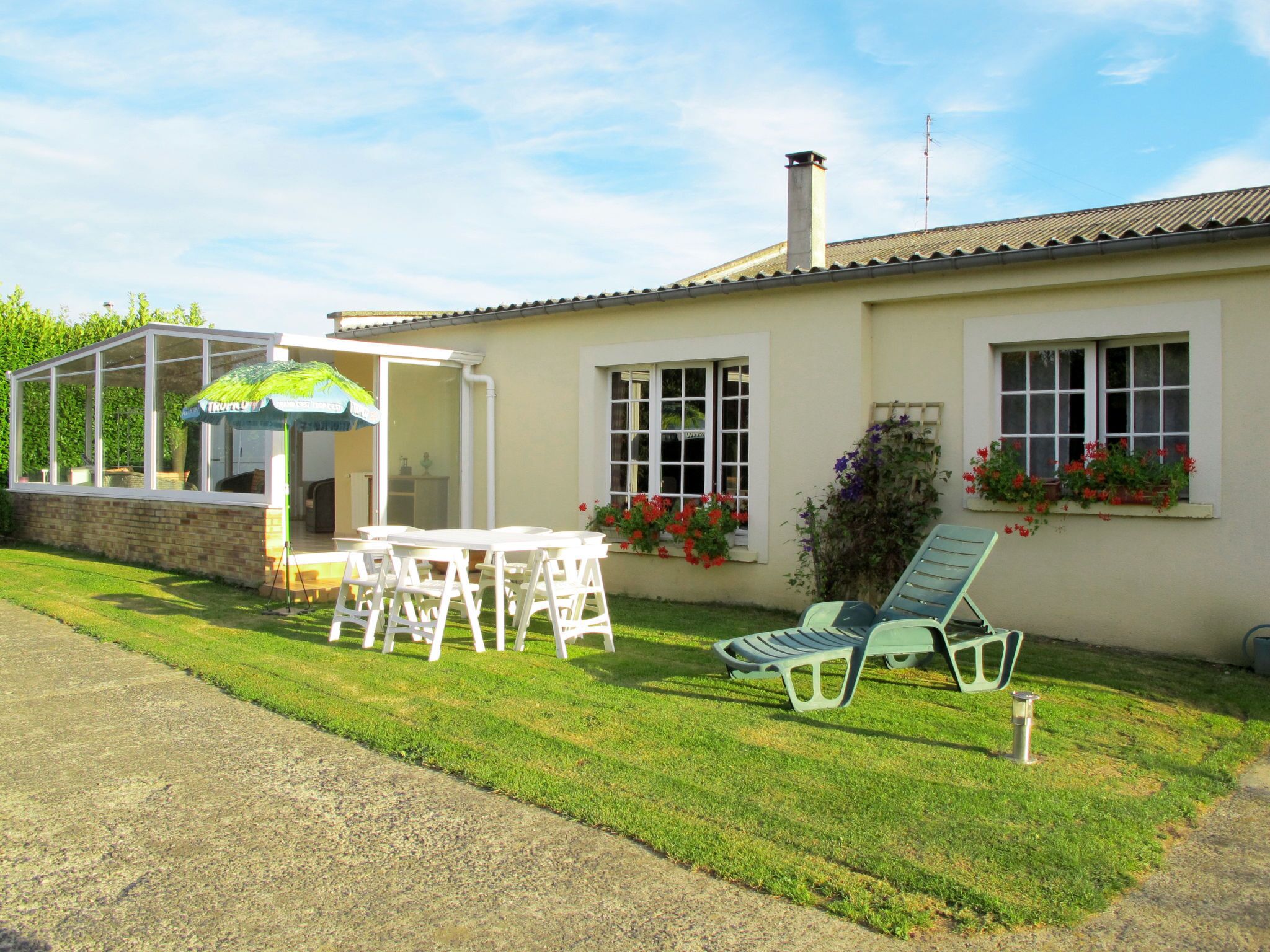A house with a patio, a conservatory, and a lawn.