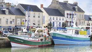 Dos barcos amarrados en un puerto con edificios al fondo.