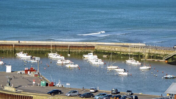 Un puerto deportivo con barcos amarrados, un muelle y un aparcamiento con coches.