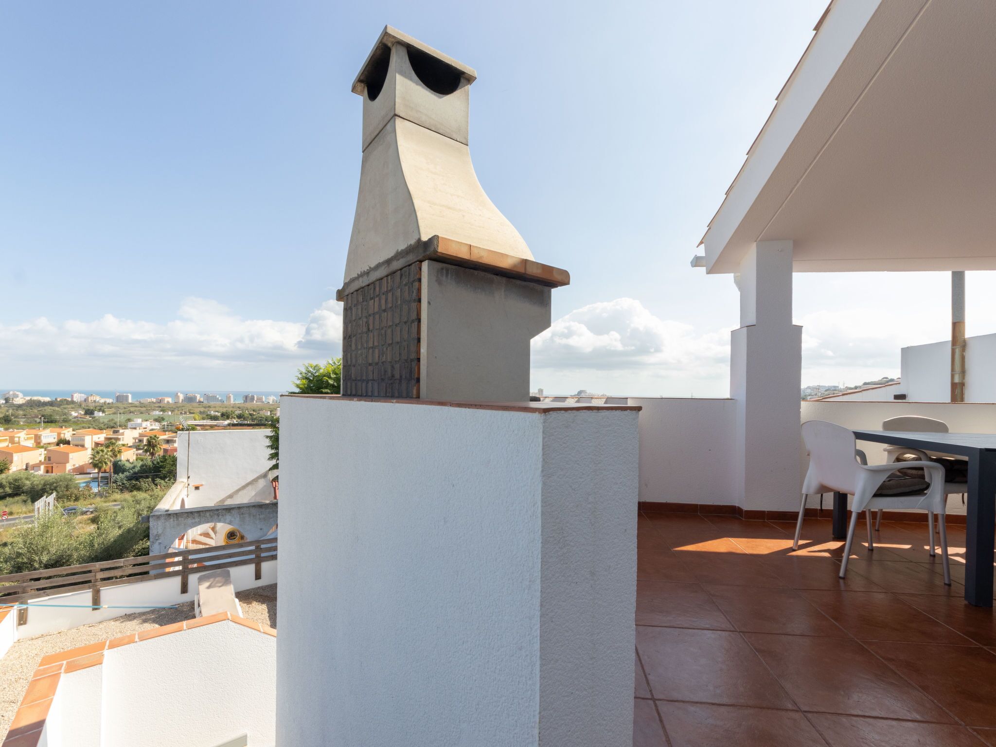 A rooftop terrace with a chimney, a dining table, and chairs.