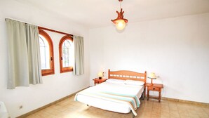 A bedroom with a bed, two bedside tables, a nightstand, a window with curtains, and a hanging light fixture. - Golf Pals by Interhome (Pals)