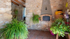 A rustic stone interior with a wood-beamed ceiling, a stone wall, and a brick fireplace.