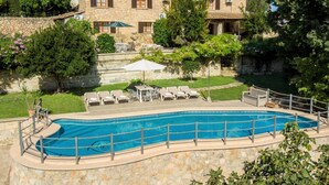 A pool area with lounge chairs and a stone wall.