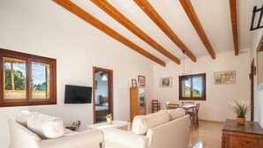 Un salon spacieux comprenant un grand canapé, une table à manger et un téléviseur fixé au mur.