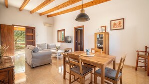 Un grand espace de vie comprenant une table à manger en bois, des chaises, un canapé et un téléviseur.