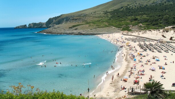 A beach with clear blue waters, sandy shore, and a hilly backdrop. - Maria Fumet by Interhome (Capdepera)