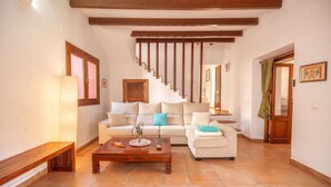 A living room with a sofa, a wooden coffee table, and a staircase. - Maria Fumet by Interhome (Capdepera)