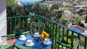 A balcony with a table set for two, overlooking a coastal village and the sea. - S'Olivera Nº3 by Interhome (Sa Riera)