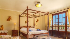 A four-poster bed with a wooden frame, a bedside table with a lamp, and a bench.