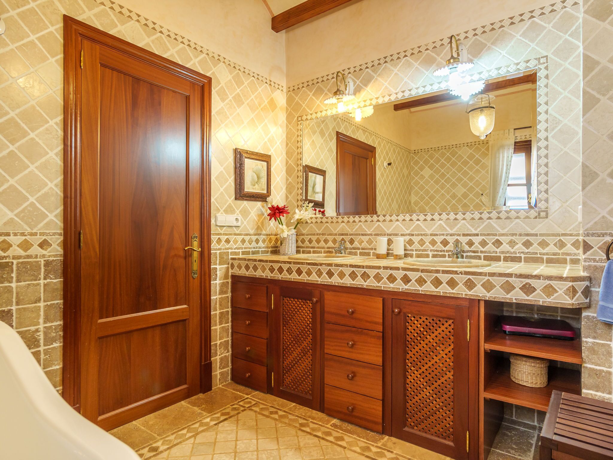 A bathroom with a wooden door, a large mirror, a sink with a vanity, and a bathtub.