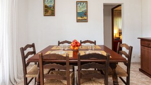 A dining area with a wooden table and chairs, a fruit bowl, and two paintings on the wall. - S'Olivera Nº1 by Interhome (Sa Riera)