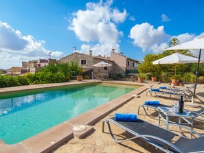 A pool area with lounge chairs and umbrellas, surrounded by stone buildings and greenery. - Sa Rota by Interhome (Biniamar)