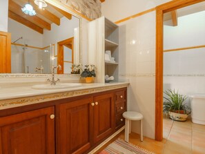 A bathroom with a wooden vanity, a large mirror, a sink, and a potted plant. - Sa Rota by Interhome (Biniamar)