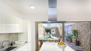 Une cuisine moderne avec des meubles blancs, un plan de travail en marbre et un îlot central agrémenté d’un saladier rempli de citrons.
