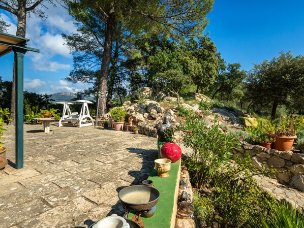 A stone patio with outdoor furniture, potted plants, and a statue.