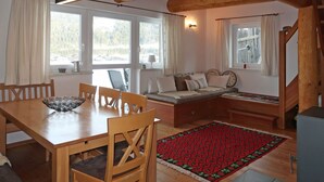 Una habitación acogedora con una mesa de madera, sillas, un sofá y un tapete rojo estampado.