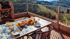 Una terraza con una mesa lista para el desayuno, con vistas a un paisaje montañoso.