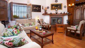 Una sala de estar acogedora con sofá, sillones, una mesa de centro, chimenea y candelabro.