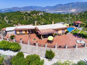 Uma grande villa com piscina, vários pátios e vista para as montanhas.