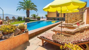 Un área de piscina con sillas de descanso y un paraguas amarillo.