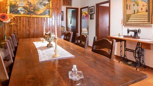 Un comedor de madera con una mesa grande, sillas, un jarrón con flores y un cuadro en la pared.