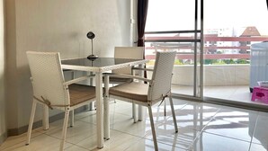 A balcony with a dining table and chairs, a small stool, and a view of buildings in the background. - 1 Bedroom Seaview 706 Kiengtalay (Pattaya)