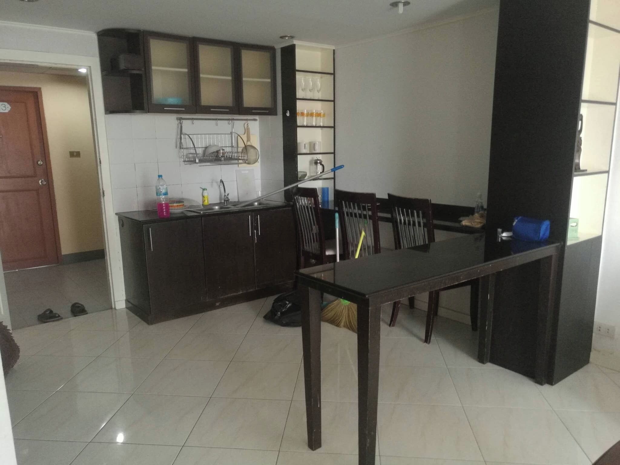 A compact kitchen with dark cabinets, a tiled backsplash, and a dining area with a table and chairs.