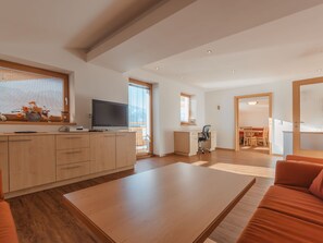 Relax in a spacious living area with a large TV, comfortable sofa, and dining space.