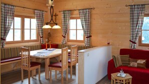 A cozy cabin interior with a wooden dining table, chairs, a bench, a red sofa, and a small side table. - Vacation home Waltl by Interhome (Fusch)