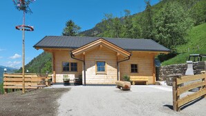 A wooden log cabin with a gravel driveway and a stone wall. - Vacation home Waltl by Interhome (Fusch)