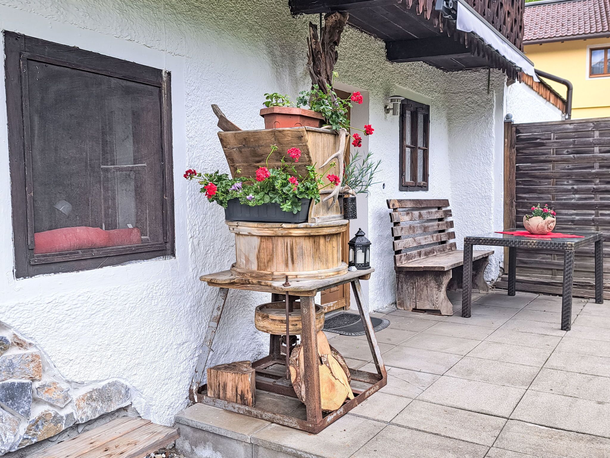 A rustic outdoor seating area with wooden furniture and a wooden planter with flowers.