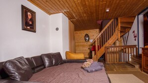 Una sala de estar acogedora con un sofá de cuero, un tapete estampado y una escalera que conduce a un nivel superior.