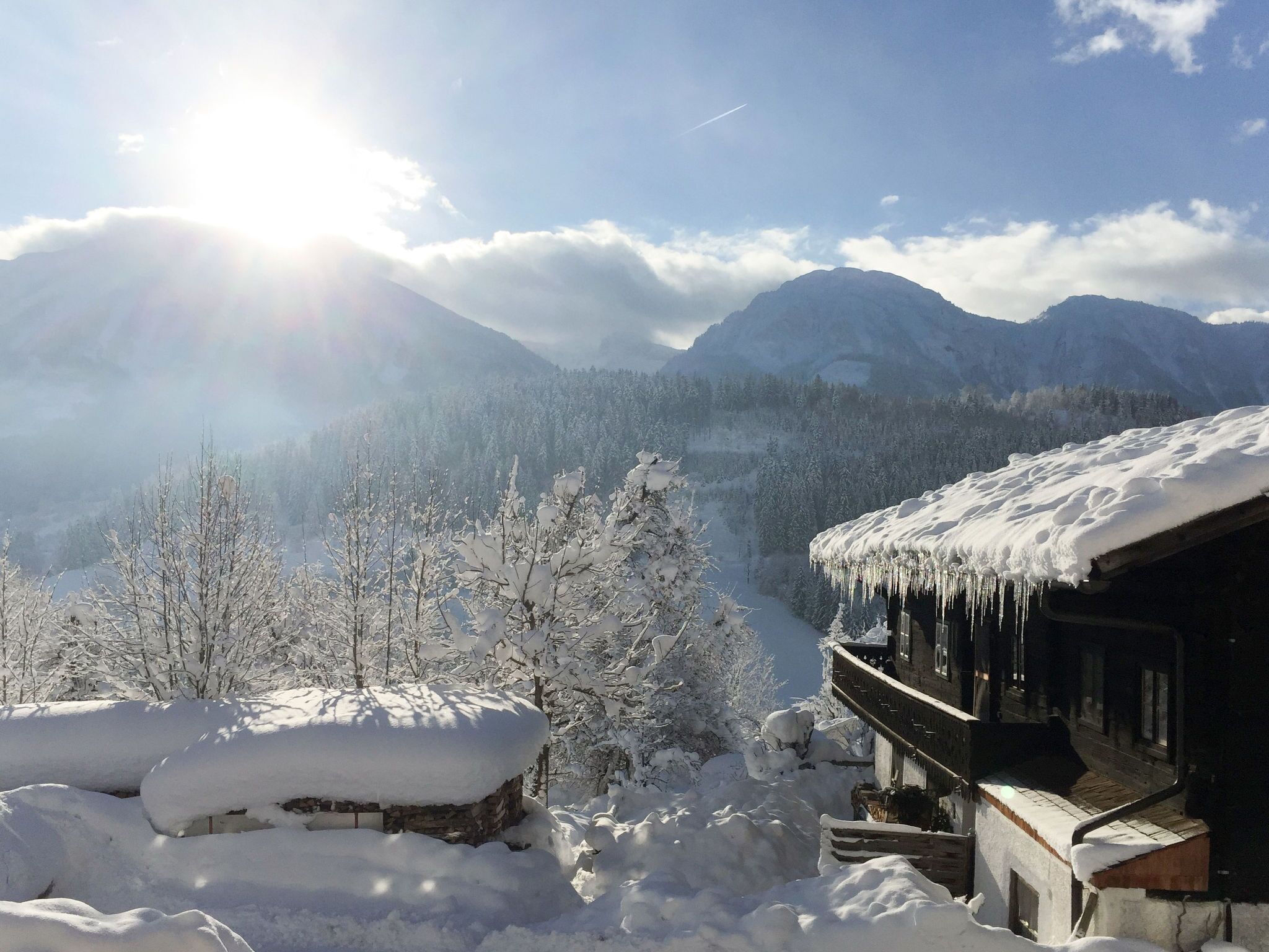 A snow-covered mountain landscape with a wooden cabin featuring a balcony.