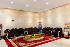 A lobby with a dark-colored sofa set, a round table, and a red carpet.