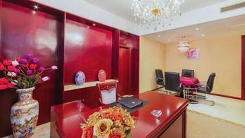 A conference room with a wooden desk, chairs, a vase with flowers, and a chandelier.
