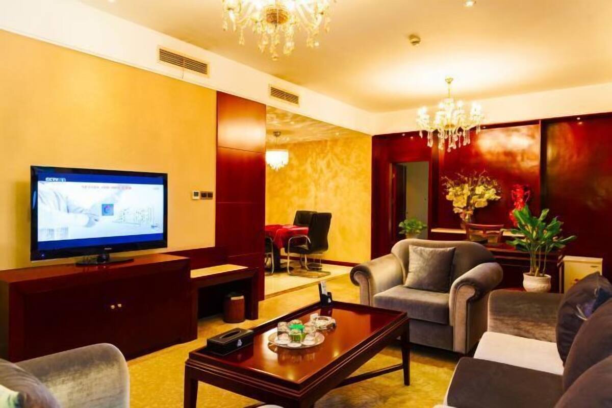 A hotel lobby with a television, seating area, and a chandelier.