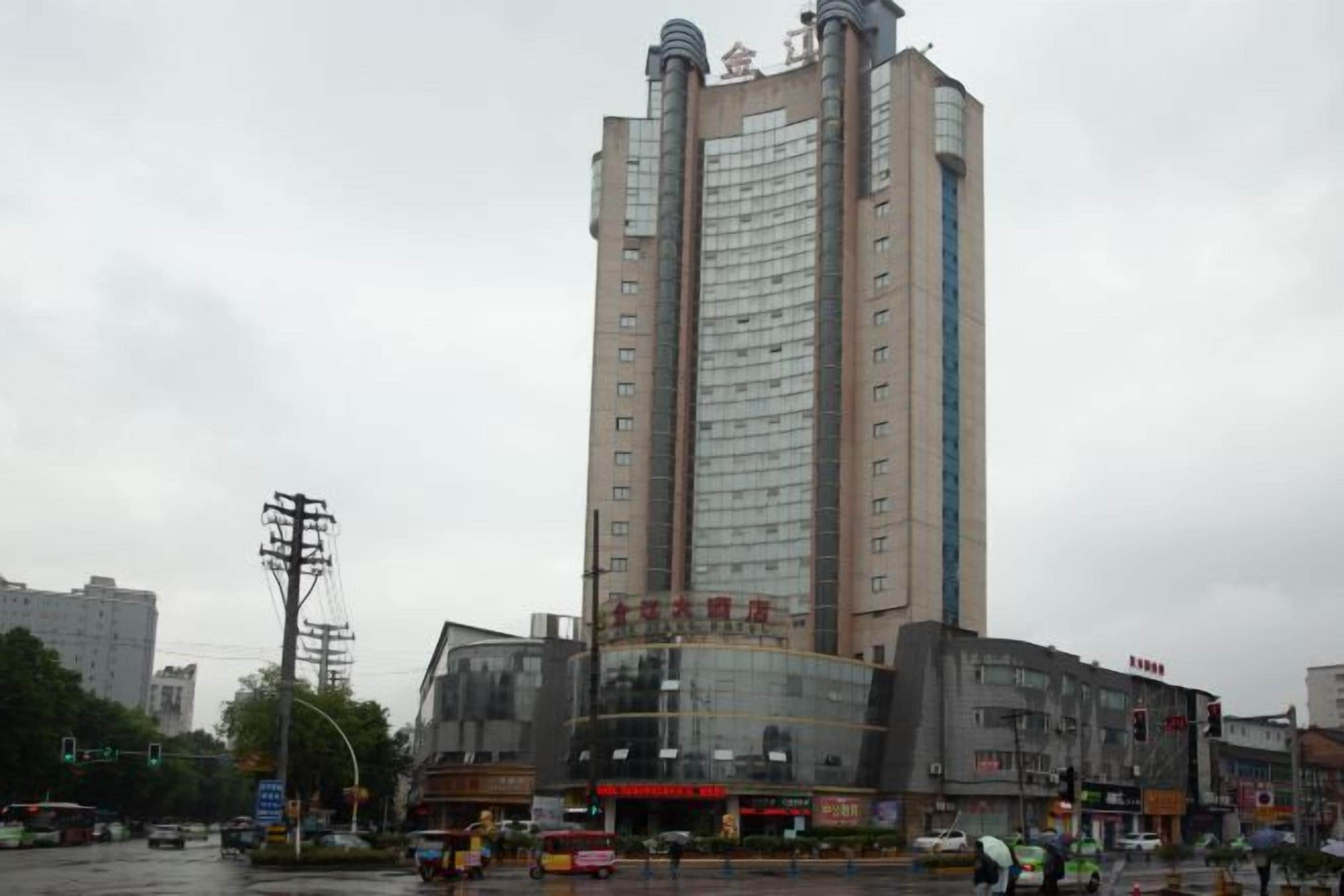 Um edifício de vários andares com uma torre central imponente, possivelmente um hotel ou edifício de escritórios, apresentando uma grande fachada de vidro e placas indicando ser um hotel.